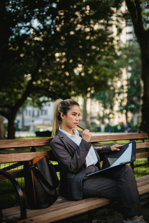 woman sitting on a park bench working on a computer