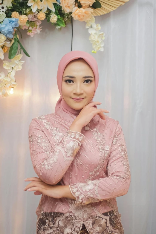 a woman posing in a pink blouse and floral garland