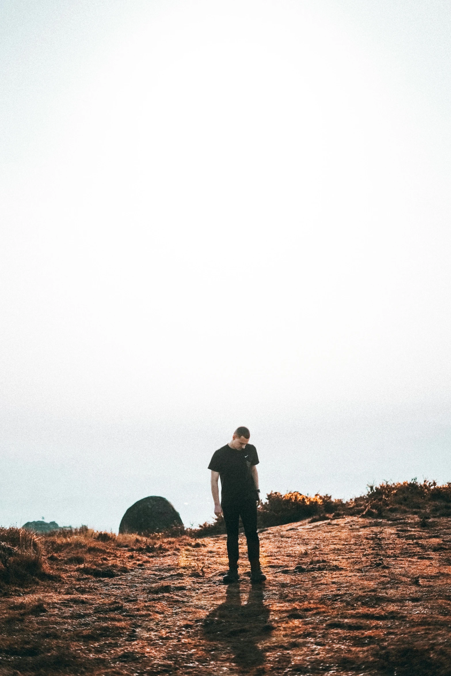 man on hilltop overlooking rocky terrain under sunny sky