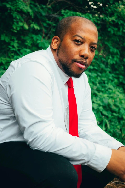 a black man sitting with his hands on his chest