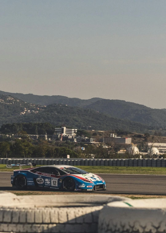 a race car drives on a track in the sun