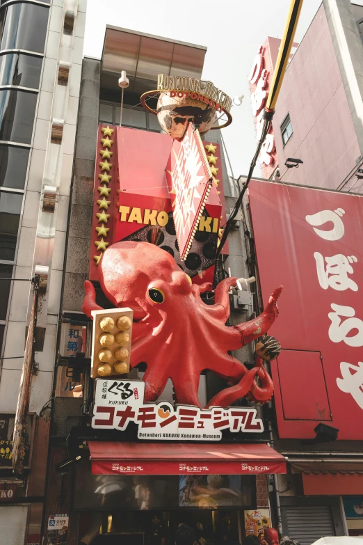 an elaborate octo restaurant sign stands near some buildings