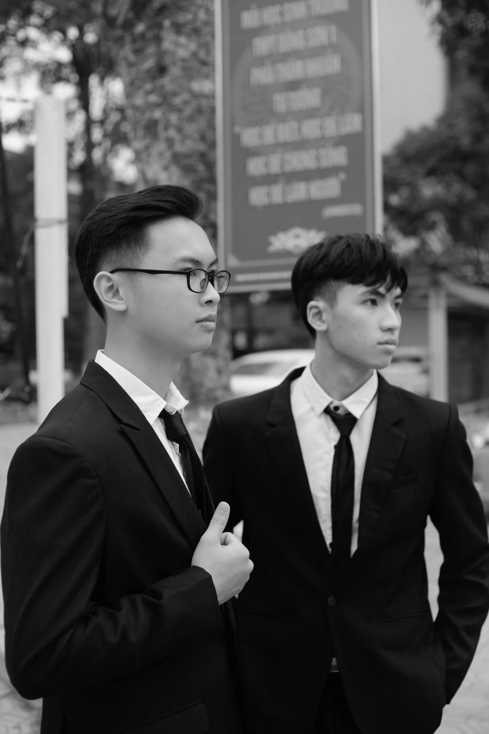 two young men in suits are standing close together