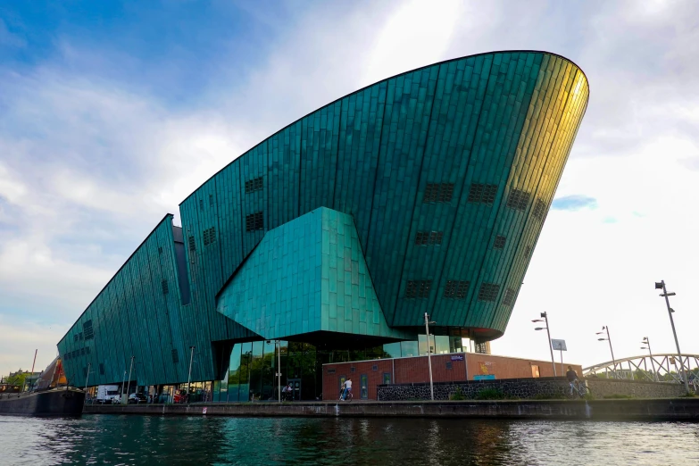 a very large curved building with a body of water