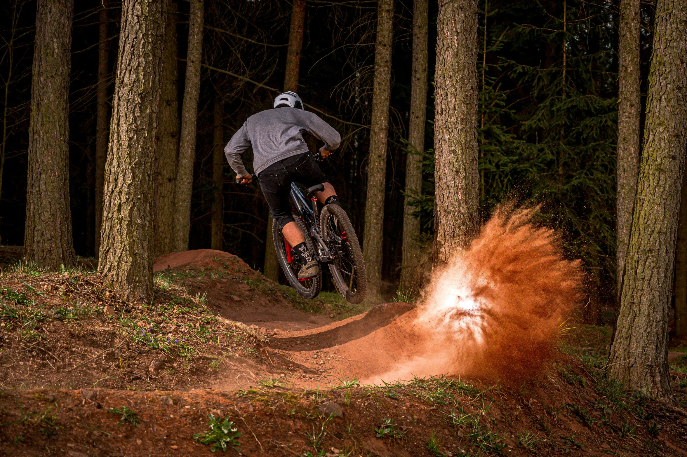 a man riding on the back of a dirt bike through a forest