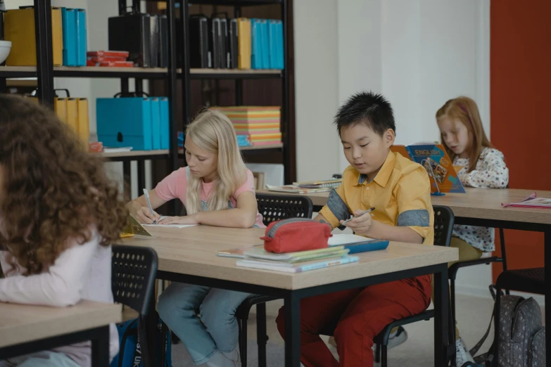 two children and an adult work together at desks in a classroom