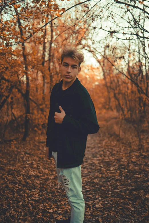 a person posing in the woods near many trees