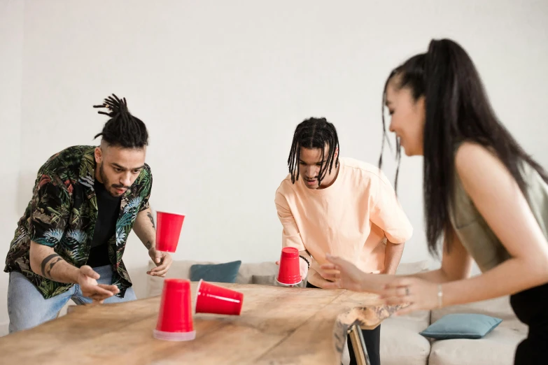 three young women and two men playing games with cups