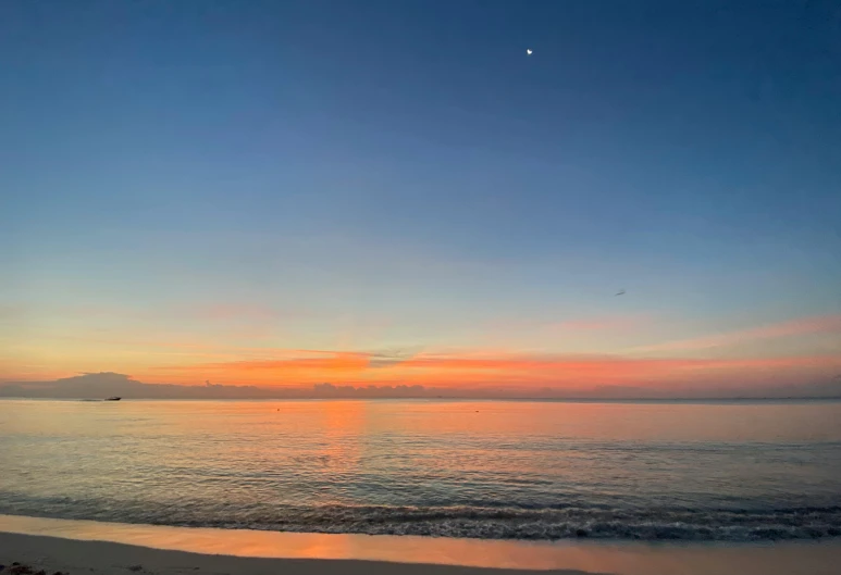 an orange sky and some water at the beach