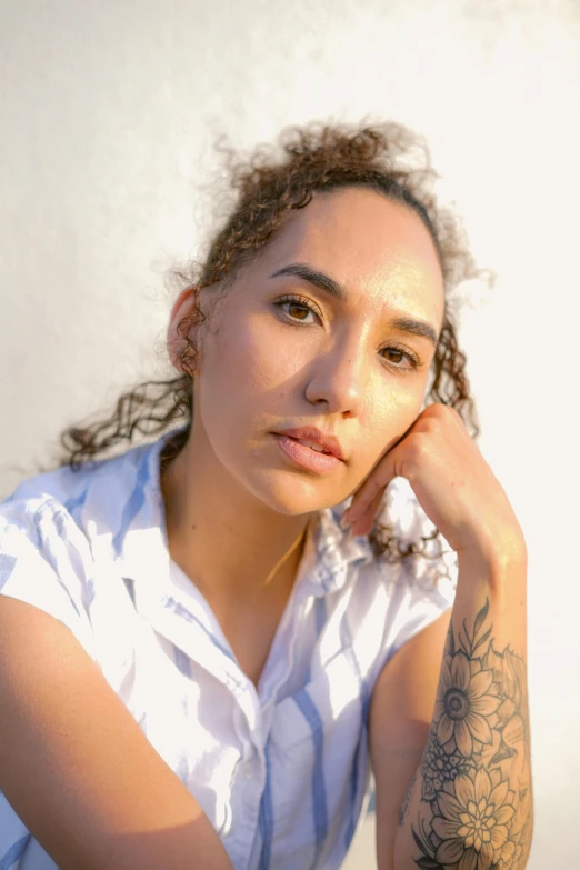 woman with tattoos resting her head on her hand