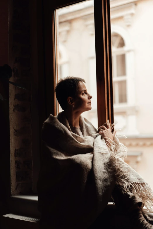 a woman that is sitting down looking out of a window