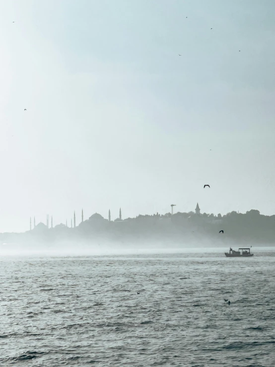 boats are sitting on the lake in the fog