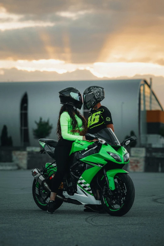 two people riding on the back of a green motorcycle