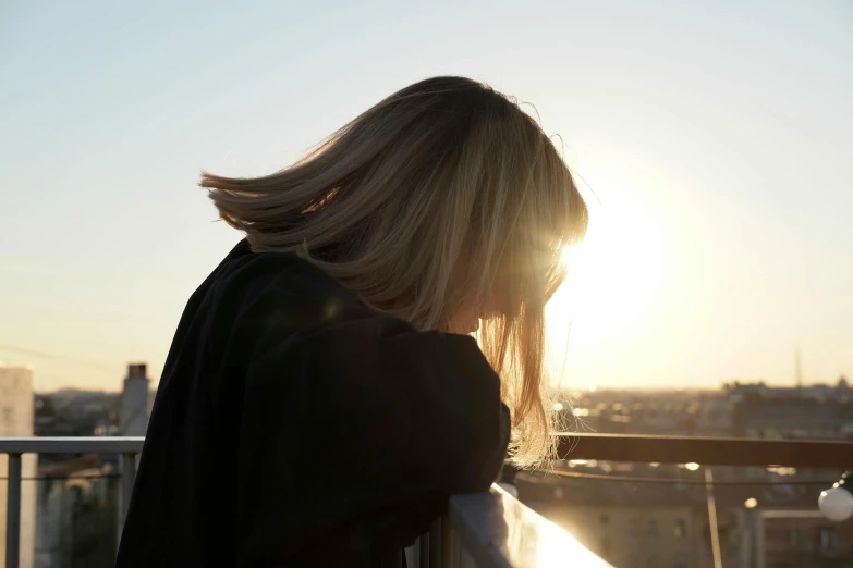 a woman looking down a balcony over looking the city