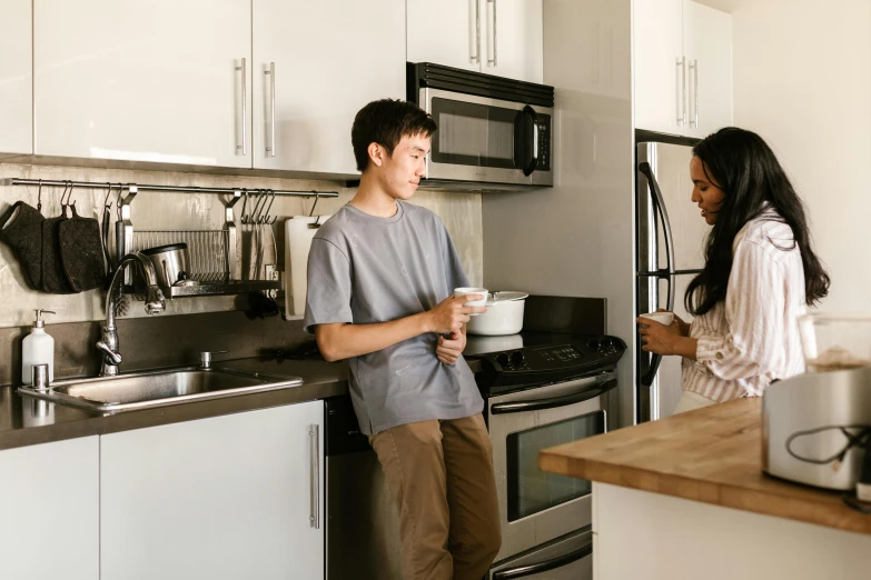 the couple is standing in the kitchen preparing some food