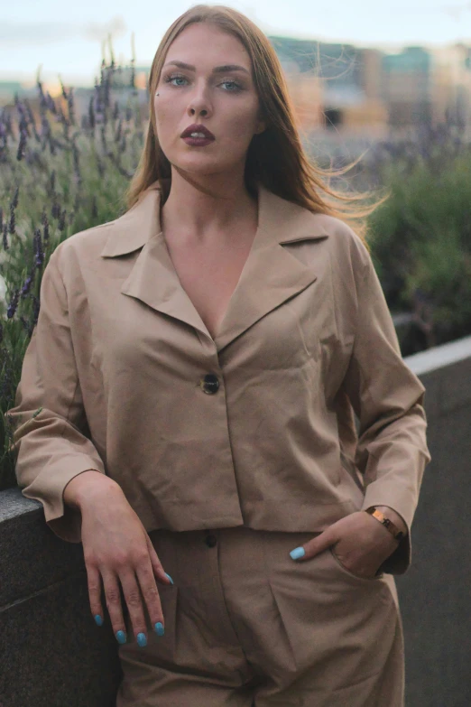 woman in tan outfit standing next to a planter