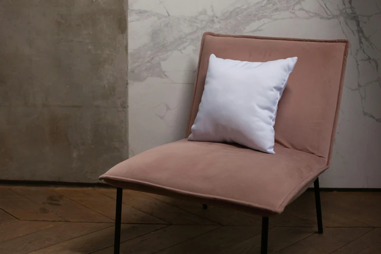 a pink chair next to a white wall and marble floor