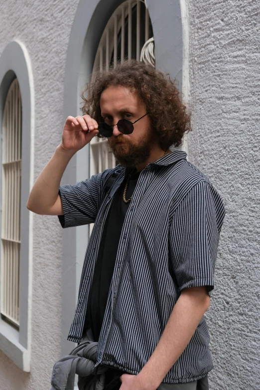 a bearded man smokes a cigarette with one hand as he walks