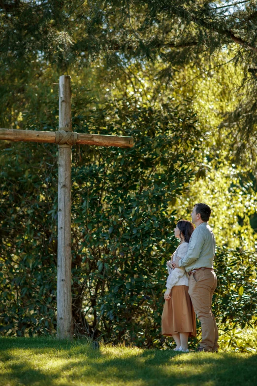 the young couple are posing in front of the cross