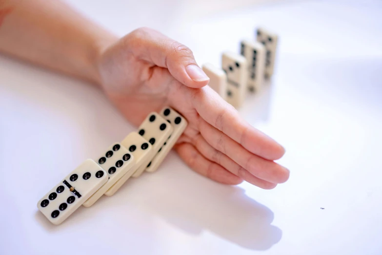 a hand reaches out for dominoes to play