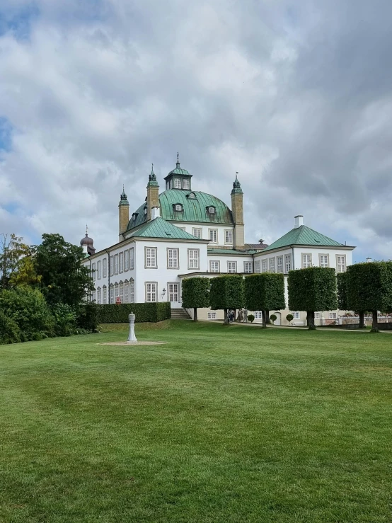 an ornate mansion sits in the middle of a green field