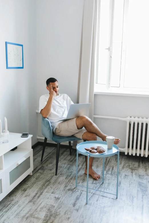 a man sitting in a chair with a laptop and holding his foot up