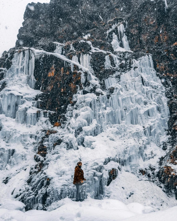 two people on a snow covered mountain with a waterfall