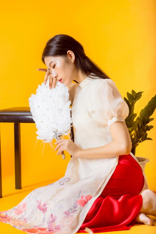 woman in white blouse and red skirt holding bouquet of flowers