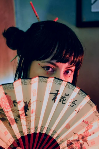 a woman holding a fan up in her hand
