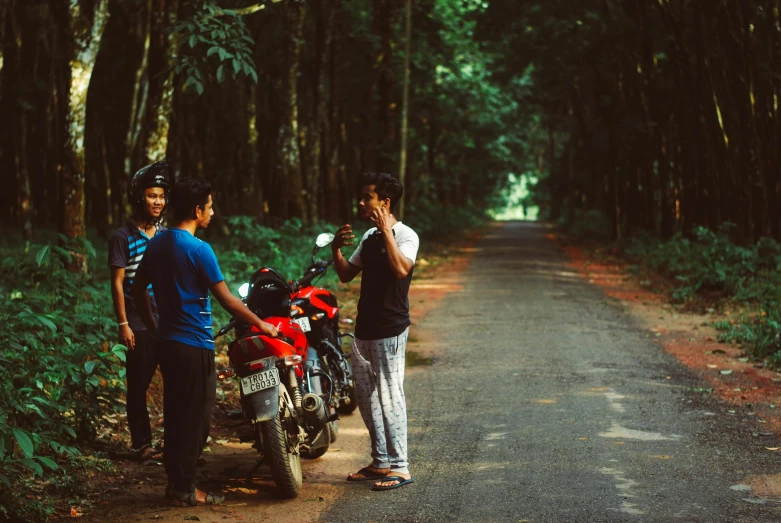 two boys stand next to their motor bikes