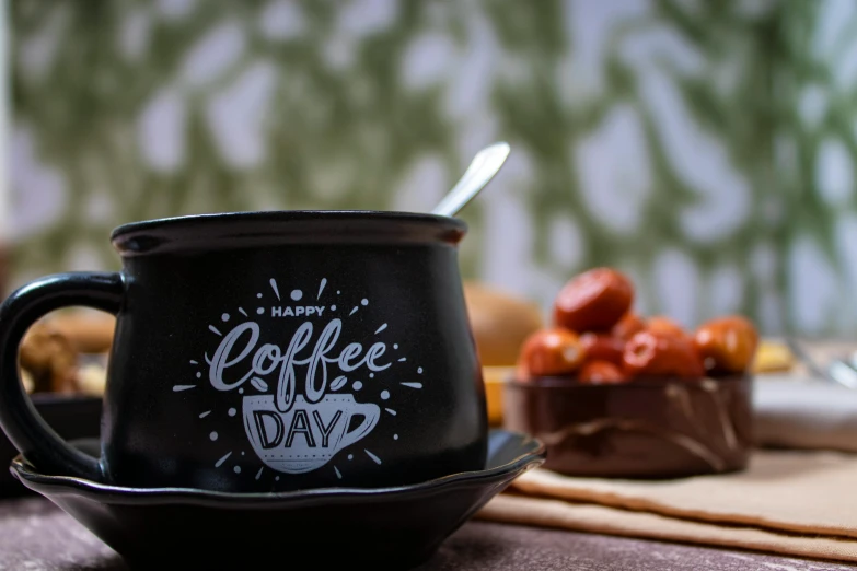 a mug sitting on top of a plate near a bowl of cherries