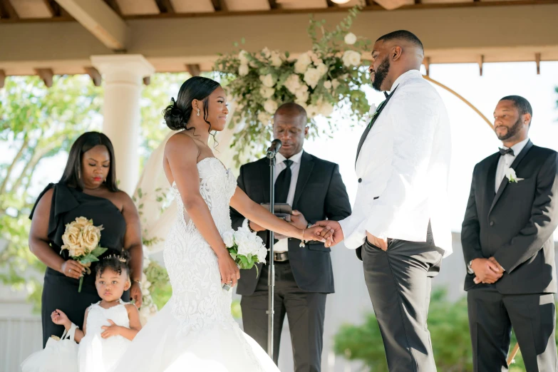 a bride and groom hold hands as their guests look on