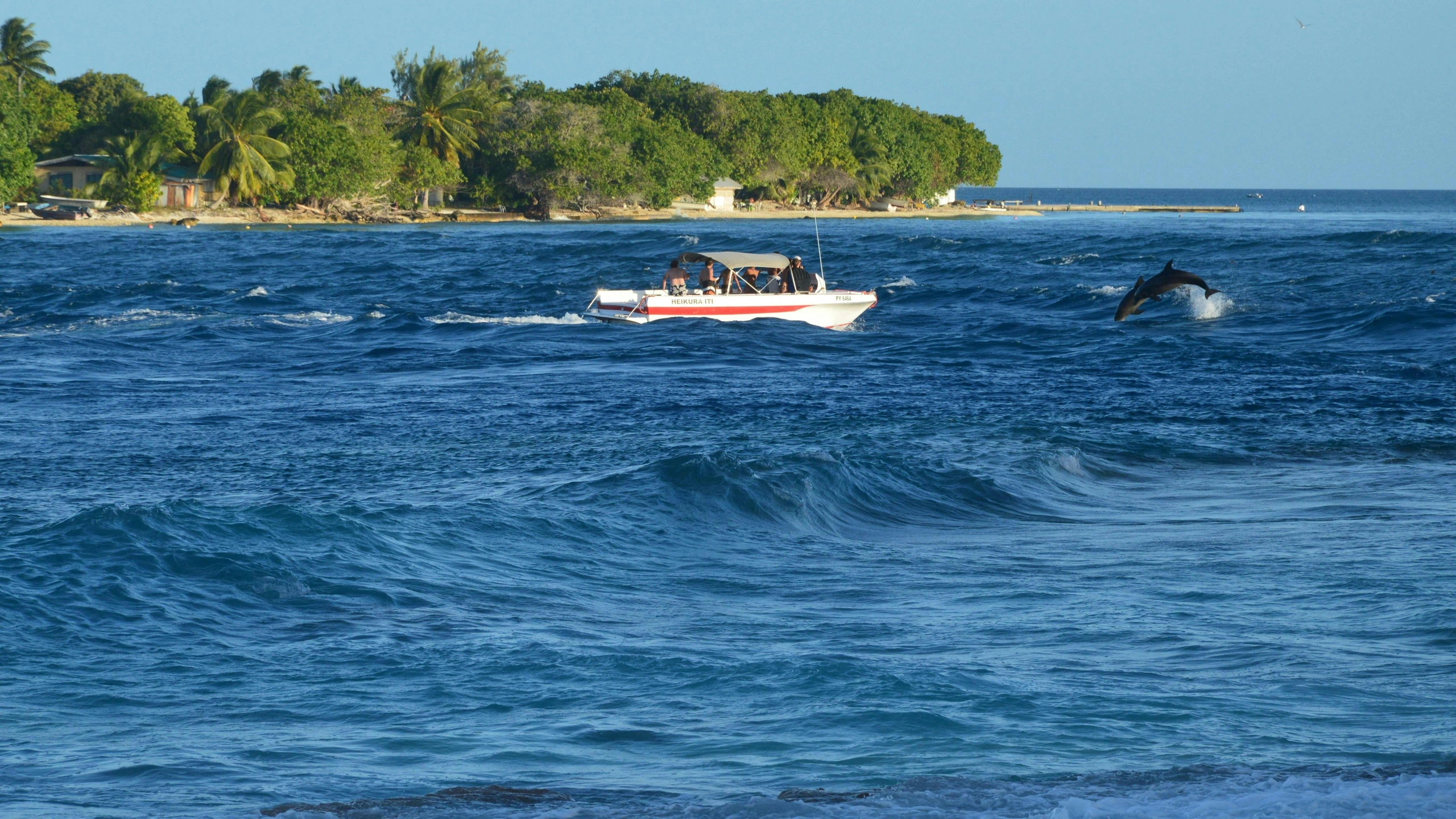 a boat driving through the water on a clear day