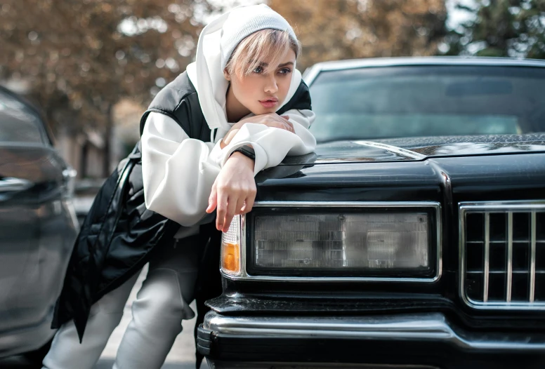 woman leaning on the hood of a black truck