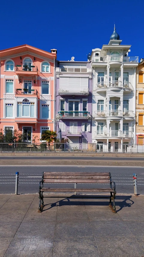 several multi - colored houses with one bench sitting in front of it