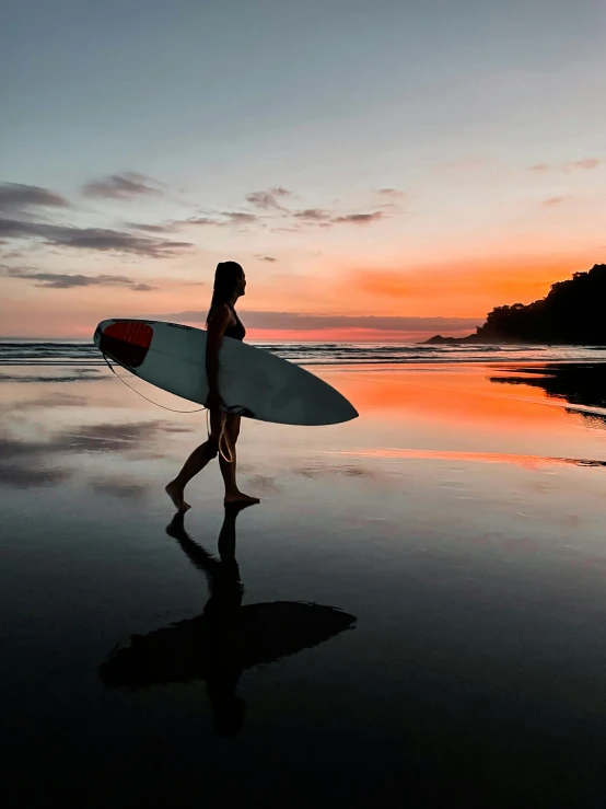 a young person is walking on a beach with a surfboard