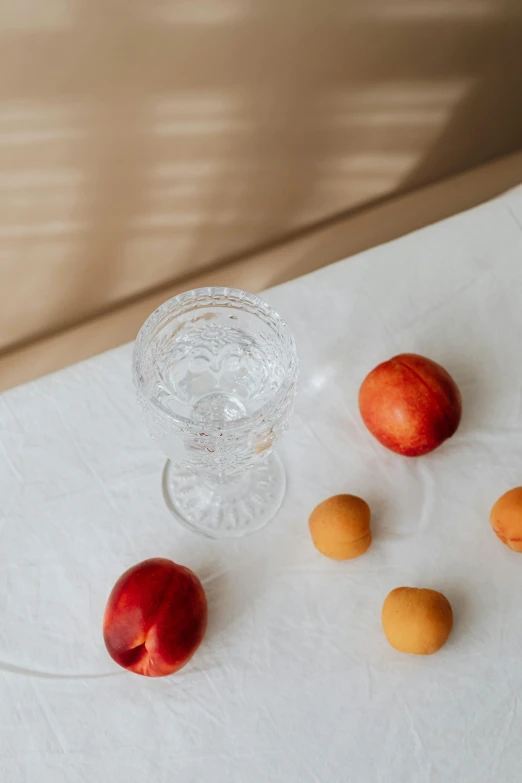 a clear glass with oranges and an apple on the table