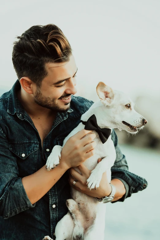 man in jacket and bow tie holding a small dog