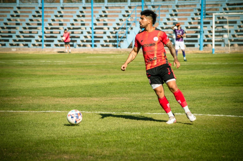 a young man in red kicking a soccer ball