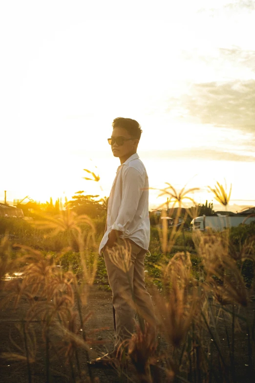 a man standing on top of a field near tall grass