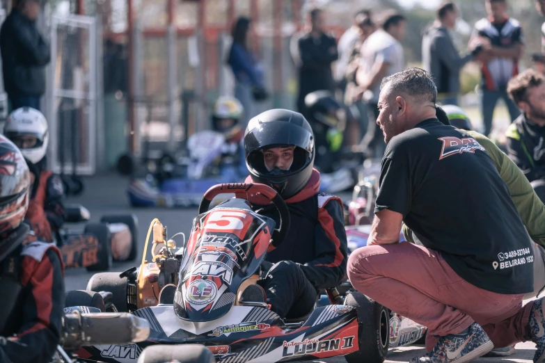 a person crouches down while one kneels next to a go kart racer