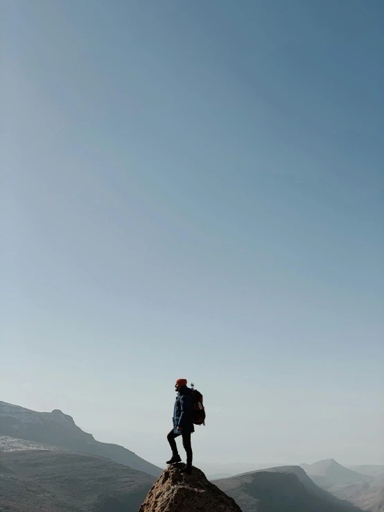 a man standing on top of a mountain in a blue sky