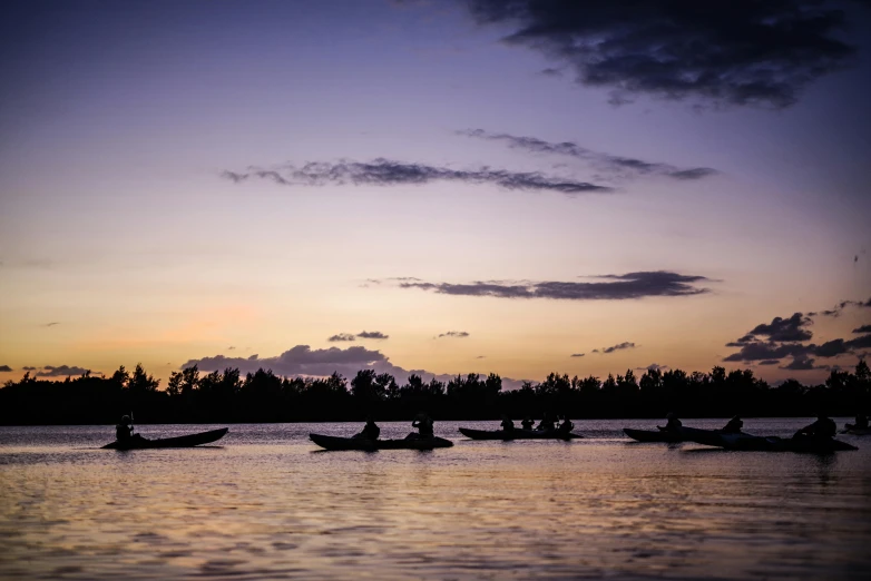 some canoes are in the water at sunset