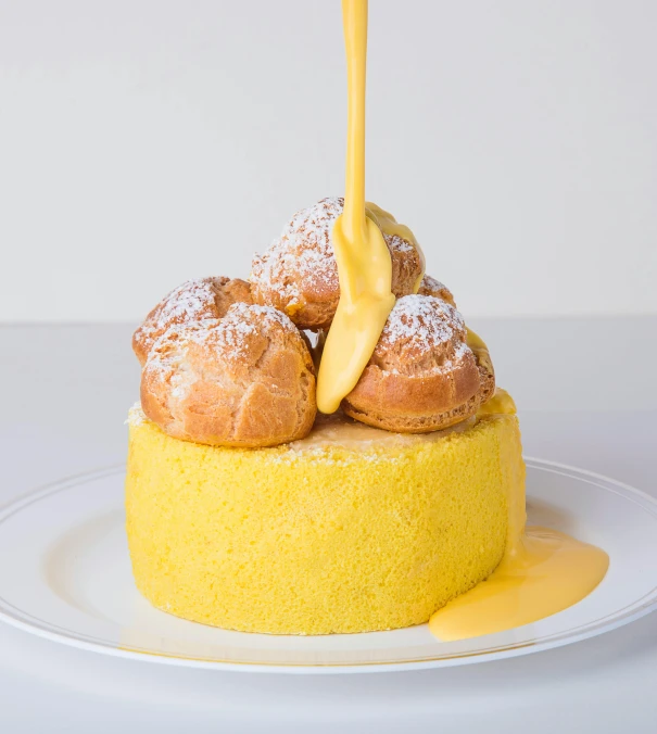 a yellow pastry topped with powdered sugar and drizzling on top of it