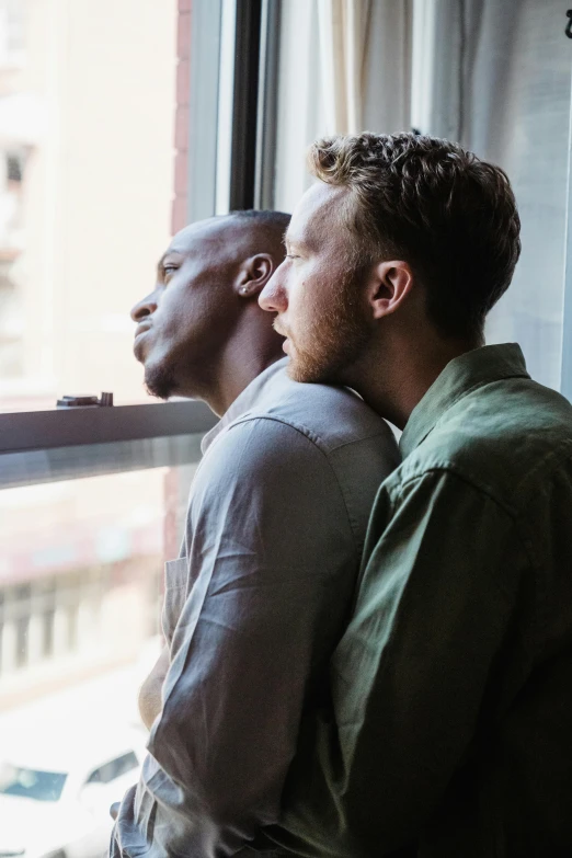 two people standing together looking out a window