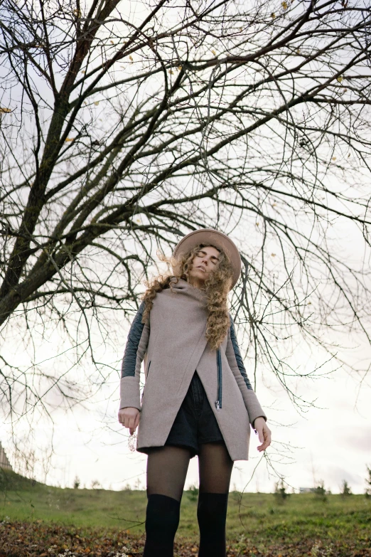 a girl standing in a field with a hat on