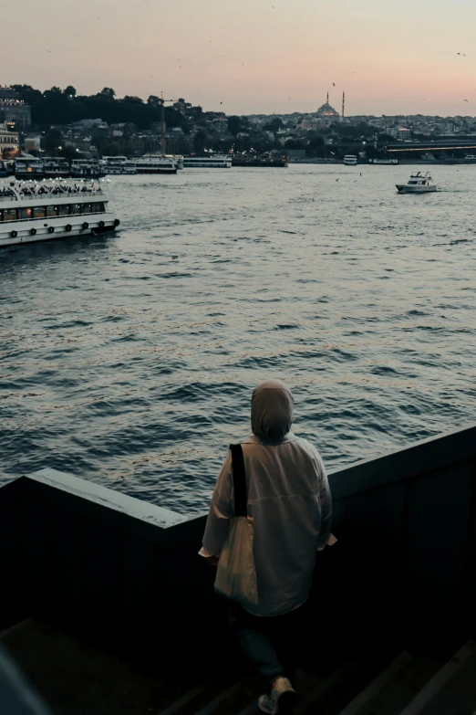 an old woman stands on a railing overlooking the water