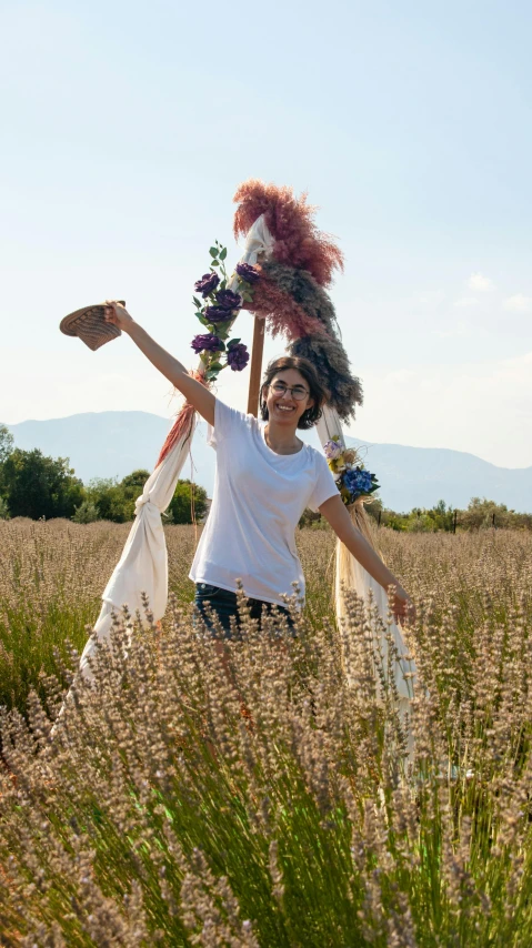 a woman in an open field carrying some flowers