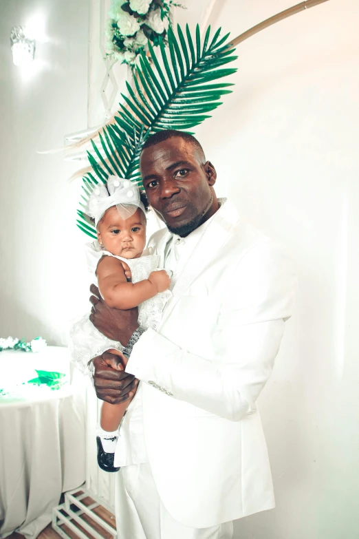 a person in white jacket holding a baby with an extra palm leaf on top