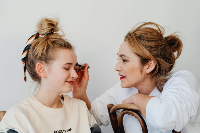 two young ladies helping each other with makeup